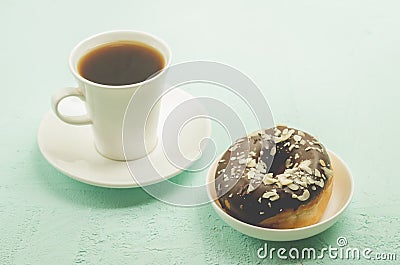 Ð¡offee break. White cup with black coffee and donat in chocolate glaze Stock Photo